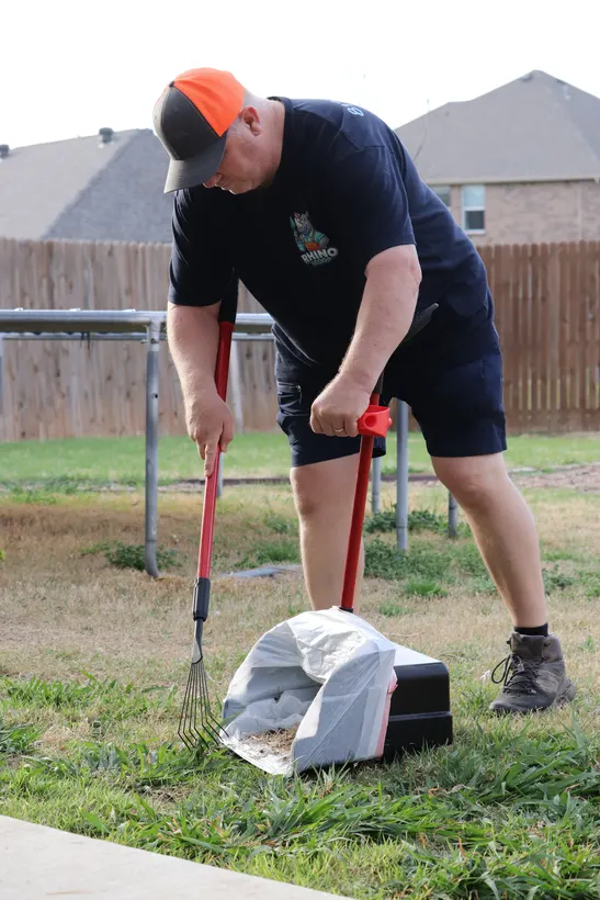 Paul scooping a Fort Worth backyard with a rake and pan